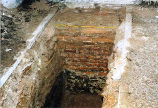 Vista de una zanja en el claustro, nótese en el cimiento el alquitrán puesto en la parte inferior coincidente con la tierra negra.